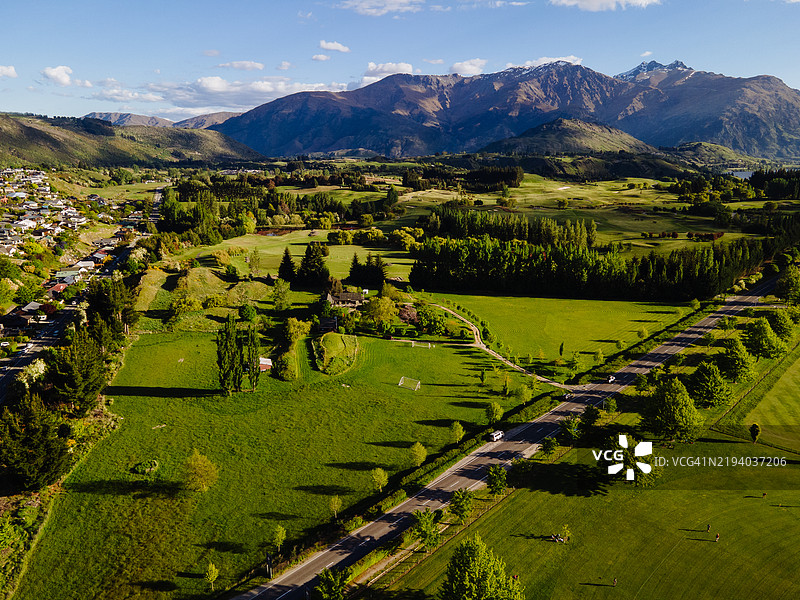 鸟瞰郁郁葱葱的乡村，背景是山脉，展现出生机勃勃的乡村风景和零星的树木。图片素材