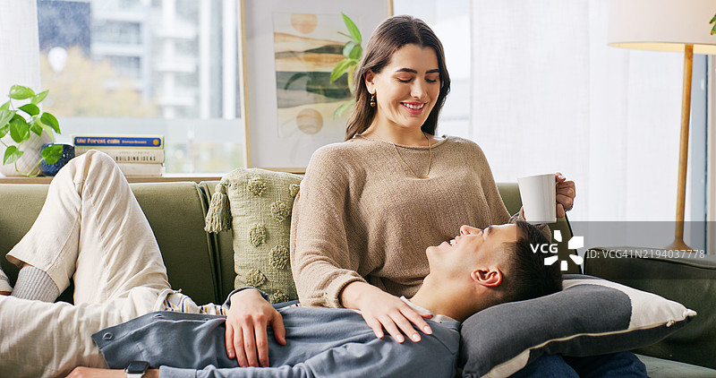 咖啡，放松或快乐的情侣在沙发上交谈，互相支持或建立安全感。人们在客厅里开玩笑或因有趣的对话而大笑，以爱或关心来建立联系。图片素材