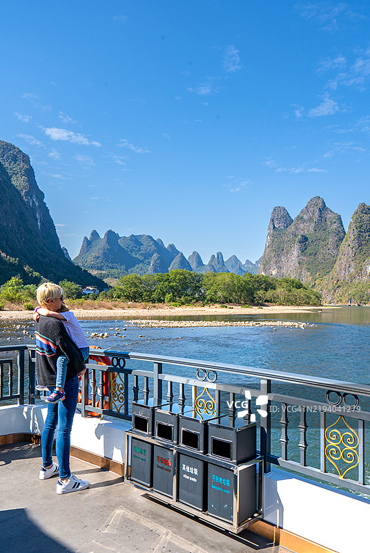 母女俩在桂林阳朔县的遇龙河风景区和漓江欣赏令人叹为观止的美丽景色和壮观的石灰岩地貌。图片素材