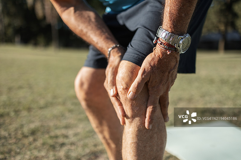 老年男子在户外晨练时感受到膝盖疼痛的特写镜头图片素材