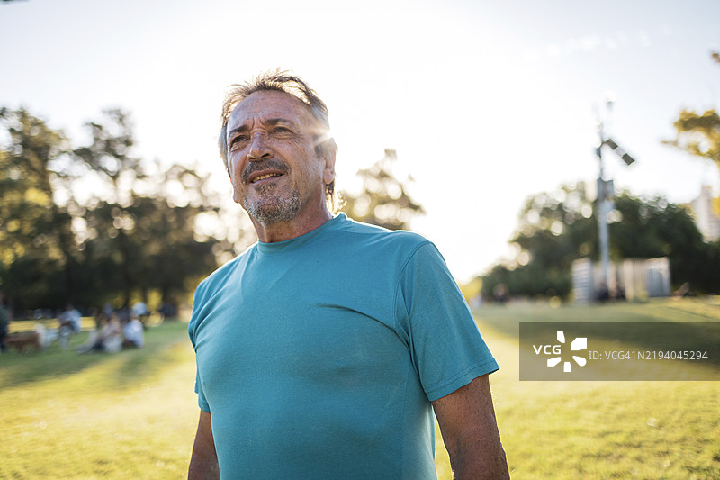 一位男士在阳光明媚的公园里享受休闲时光的肖像。图片素材