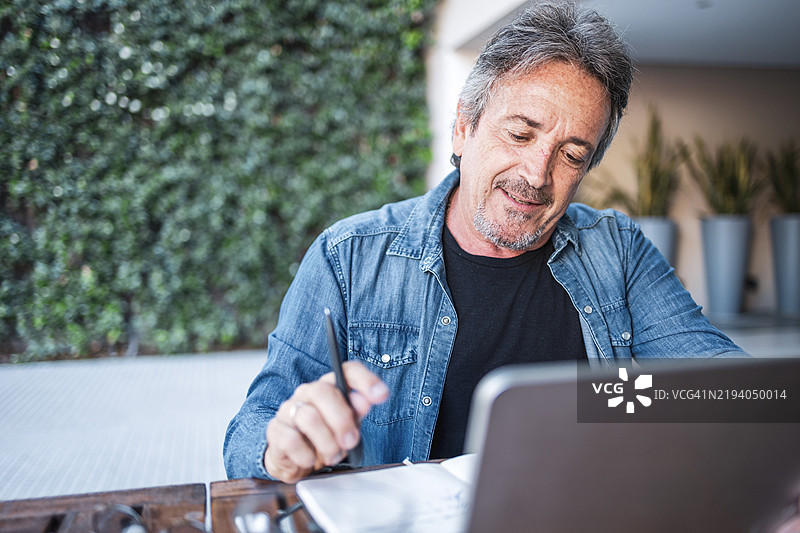 在现代舒适的环境中，男子在户外使用笔记本电脑进行在线学习图片素材