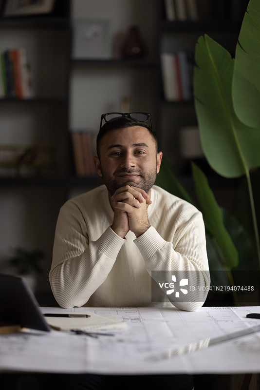 建筑师男士手持铅笔，使用笔记本电脑和蓝图进行建筑设计，工程师正在绘制施工项目概念草图。图片素材