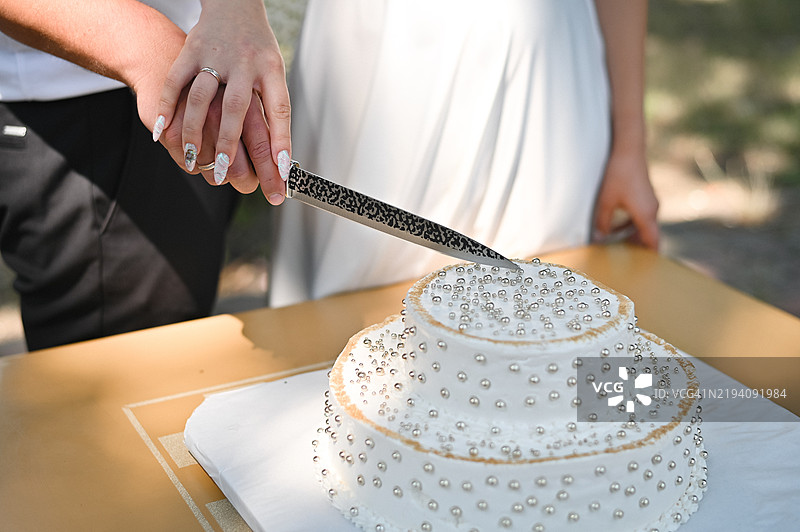 新郎新娘用刀切婚礼蛋糕的手图片素材