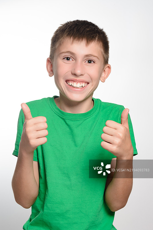 快乐的男孩竖起大拇指，脸上洋溢着积极和愉快的表情图片素材