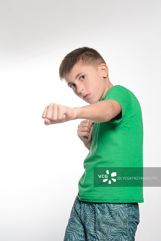 穿着绿色衬衫的小男孩顽皮地挥拳图片素材