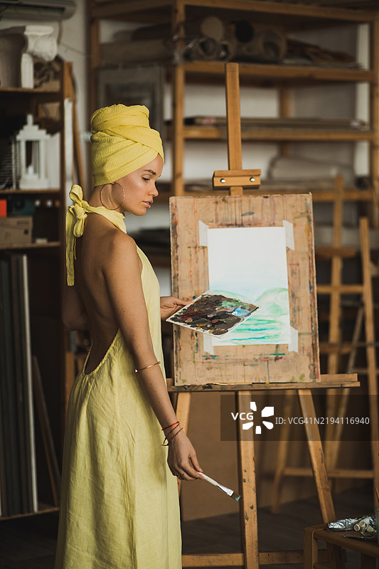 身穿黄色的女性在现代艺术工作室创作艺术作品图片素材