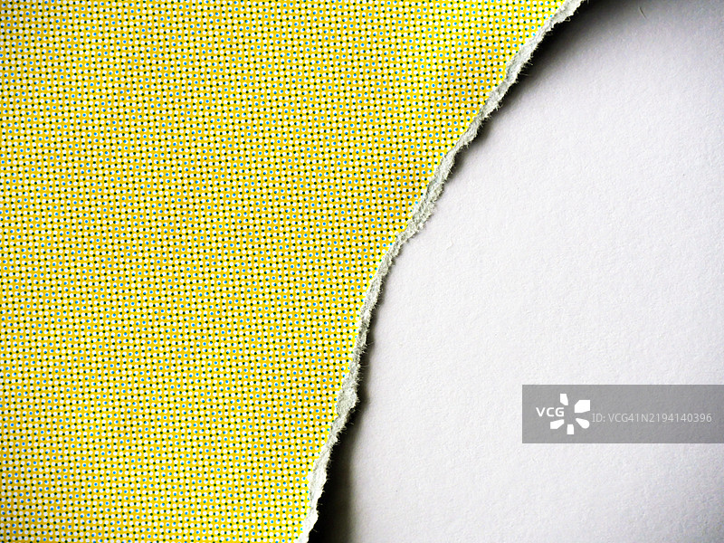 撕裂的黄海报，上面有白和蓝的圆点，放置在白纸上图片素材