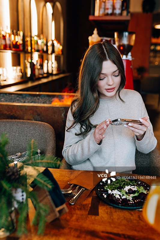 年轻女性在餐厅拍摄食物照片图片素材