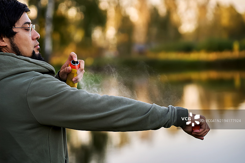 一名成年男子给自己喷洒蚊虫驱避剂。图片素材