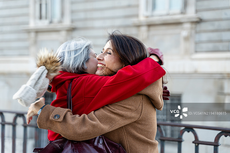 两位微笑的女性在城市户外相拥而抱图片素材