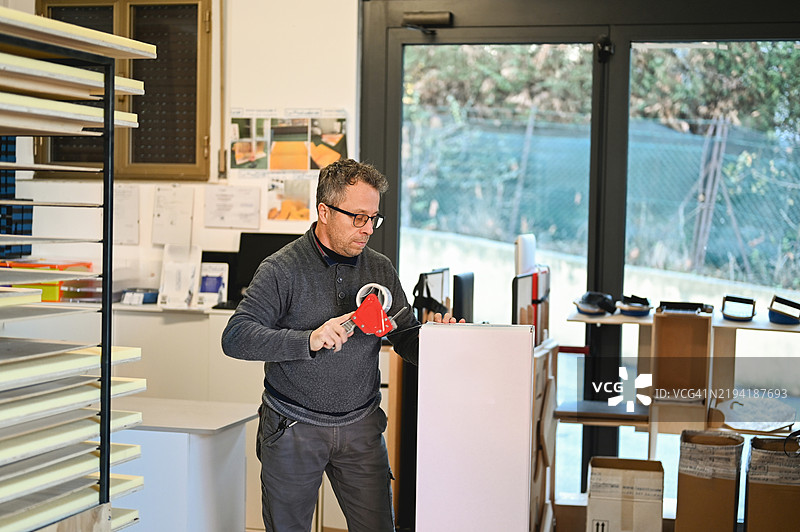 使用包装胶带分配器打包盒子图片素材