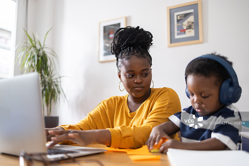 年轻母亲在家工作，同时照顾她的儿子图片素材