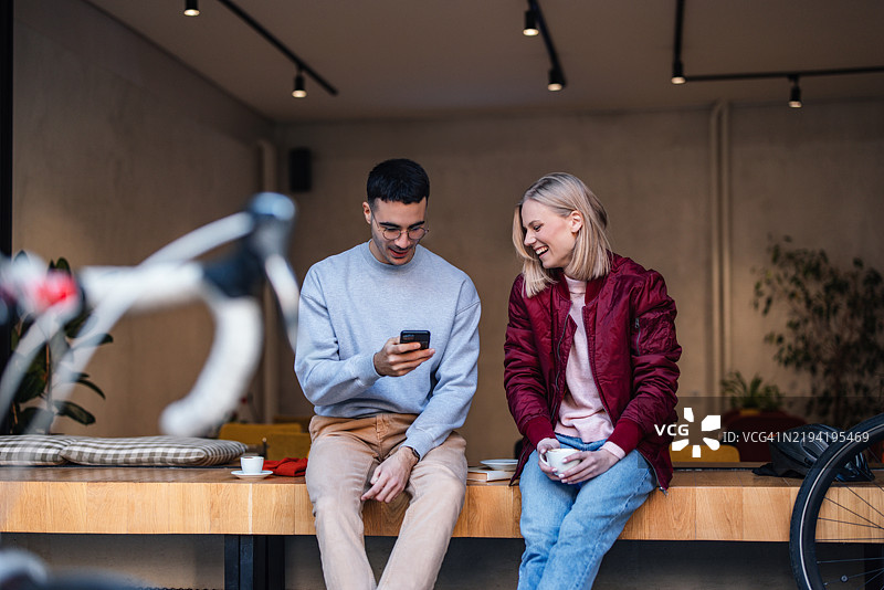 两个朋友在舒适现代的咖啡馆里一起享受咖啡图片素材