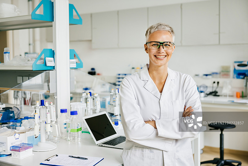 实验室中微笑并交叉双臂的女性科学家肖像图片素材