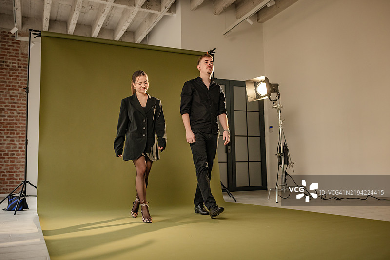 男女在绿色摄影棚背景下一起散步。图片素材