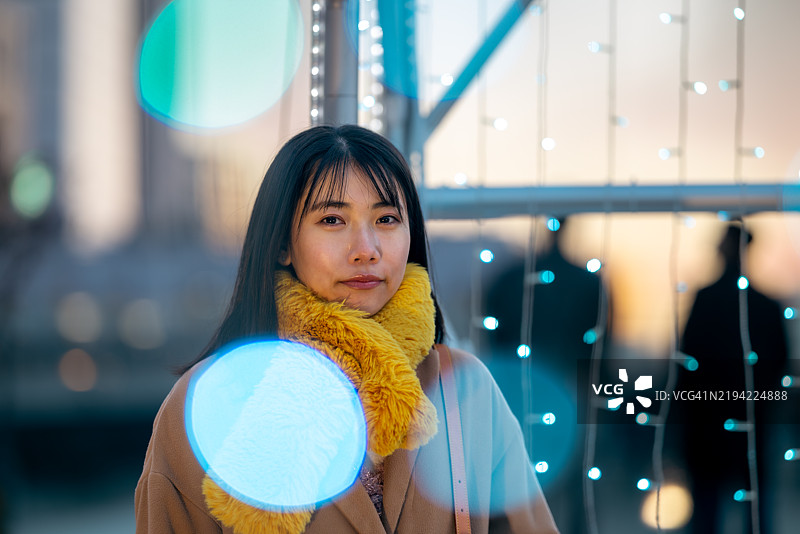 冬季黄昏时分，年轻女性自由职业者在城市中漫步的肖像图片素材