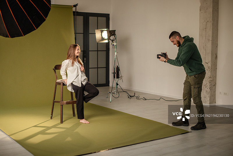 站立的摄影师在绿色背景下拍摄模特图片素材