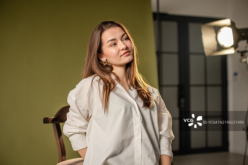 穿着白衬衫的女性被摄影棚聚光灯照亮。图片素材