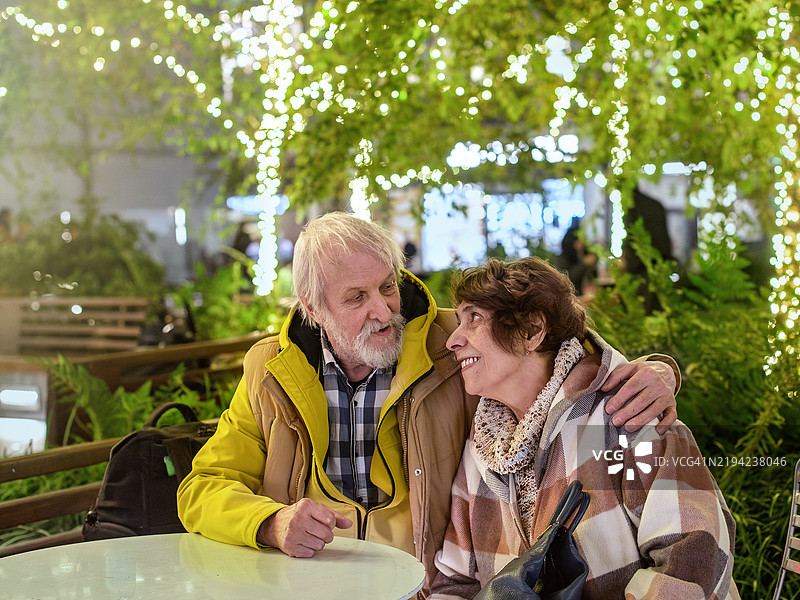 曼哈顿花园中绽放浪漫。老年夫妇在灯光下共享亲密的夜晚。图片素材