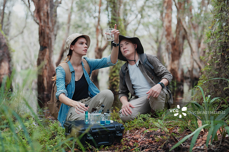 女性研究员和男性探险者在沼泽森林中分析水样图片素材