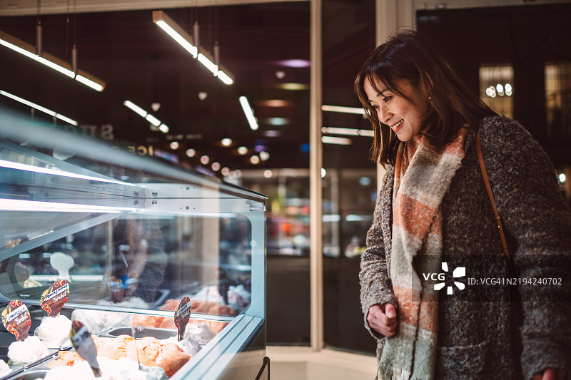 快乐的女性在冰淇淋展示柜前挑选冰淇淋图片素材