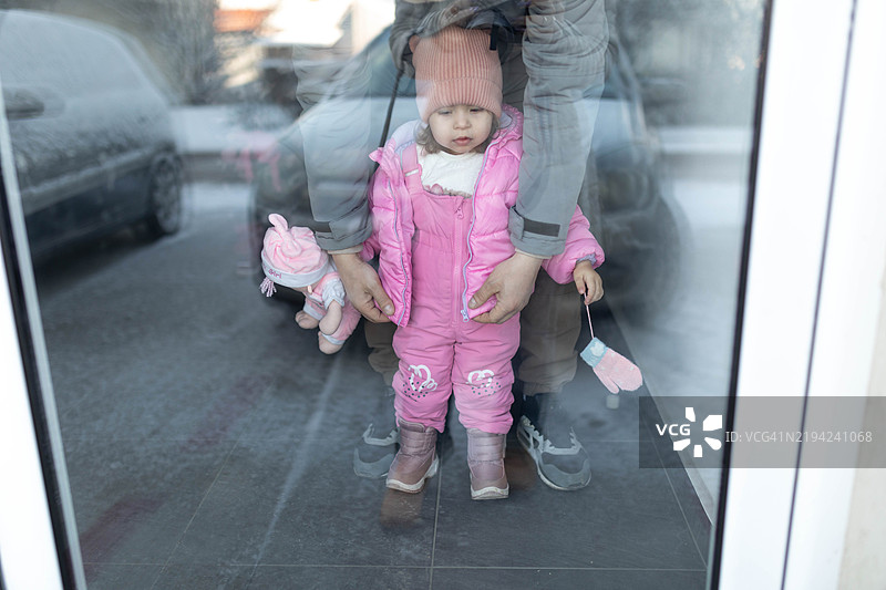 父亲在带孩子出去之前为他扣上外套。图片素材