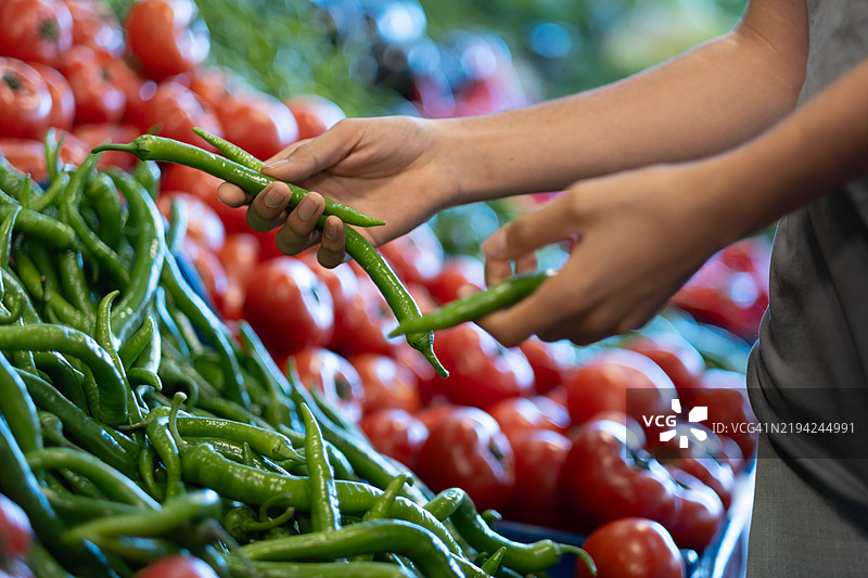 顾客在超市挑选新鲜的绿色辣椒图片素材