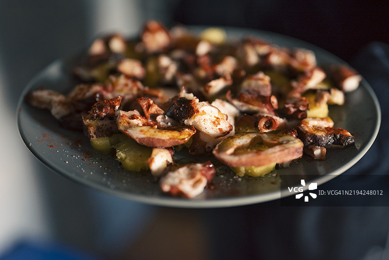 手中准备上菜的美味加利西亚章鱼配土豆特写镜头图片素材