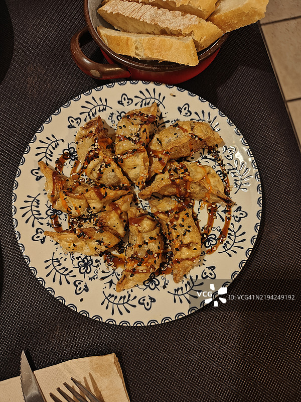 白盘上的饺子，上面淋有辣酱。图片素材