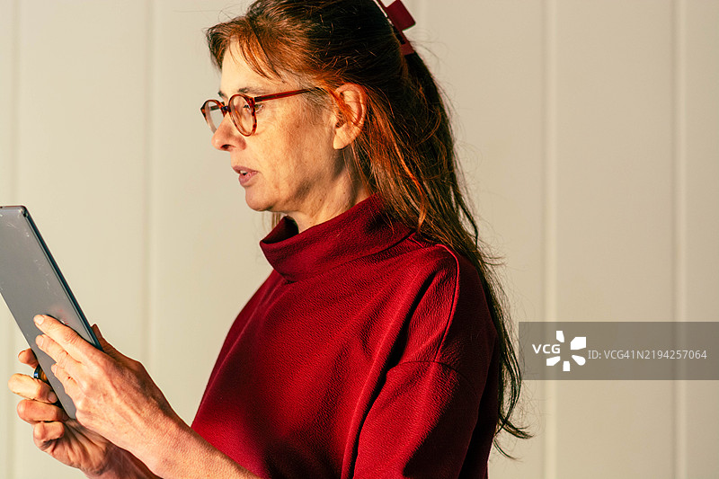 专注的成熟的女性在平板电脑上阅读电子书图片素材