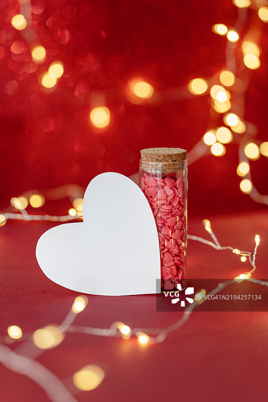 情人节装饰，包含心形卡片和装满爱情便条的罐子，背景为鲜艳的红色图片素材