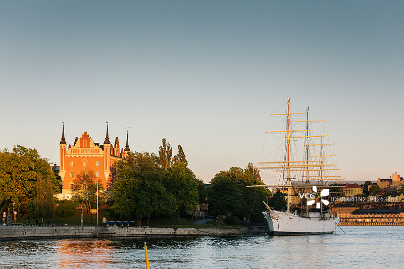 一艘古老的帆船停靠在大城市中心的一个岛屿上。图片素材