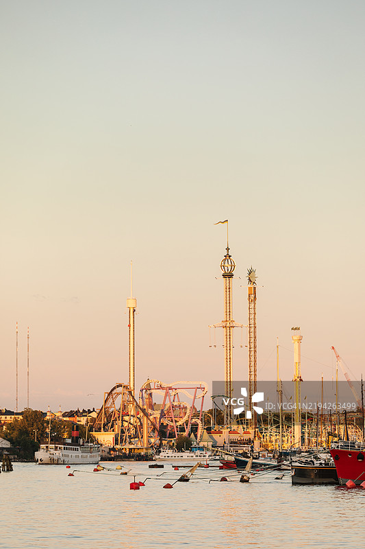 黄昏时分的游乐园，位于被水环绕的大城市中。图片素材