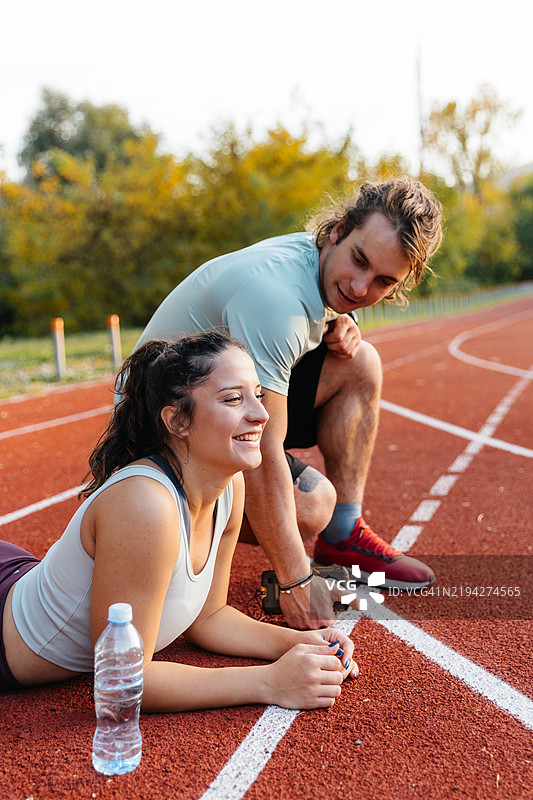 年轻男女在跑道上准备跑步图片素材