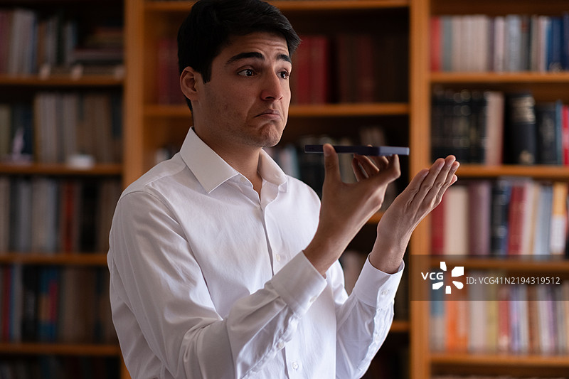 年轻男子在图书馆用手机进行视频通话图片素材