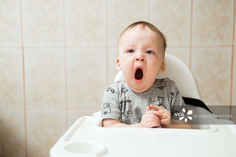 宝宝坐在高脚椅上打哈欠图片素材