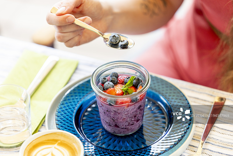 阳光明媚的夏日户外早餐桌，上面摆放着健康的酸奶和超级食品水果。图片素材