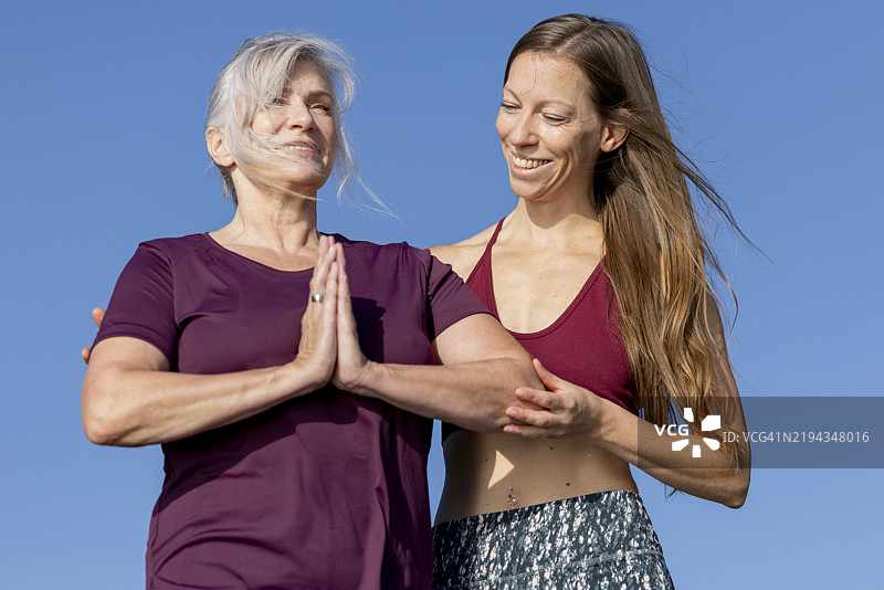 活跃、快乐的女性老年人在瑜伽静修中与她的女性私人瑜伽教练一起做瑜伽姿势图片素材