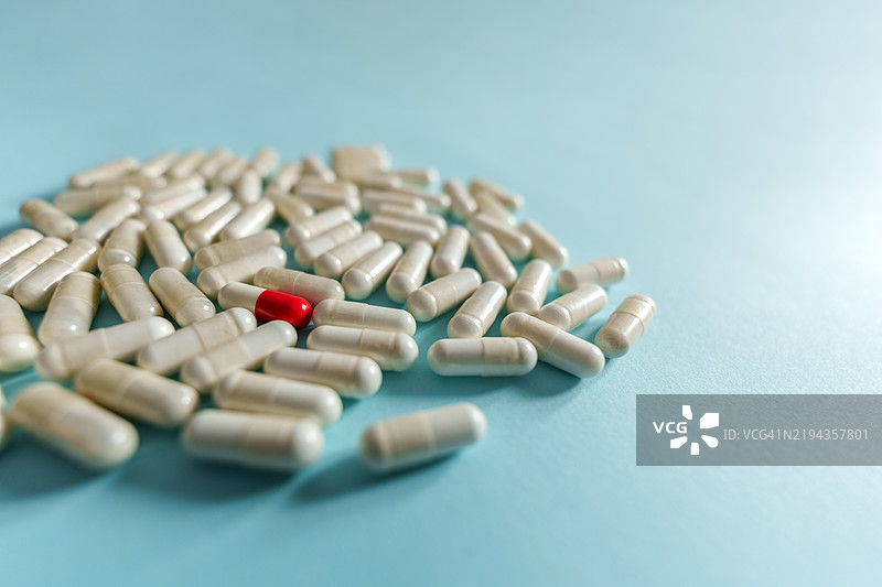 红色药丸从一群白色药丸中脱颖而出图片素材