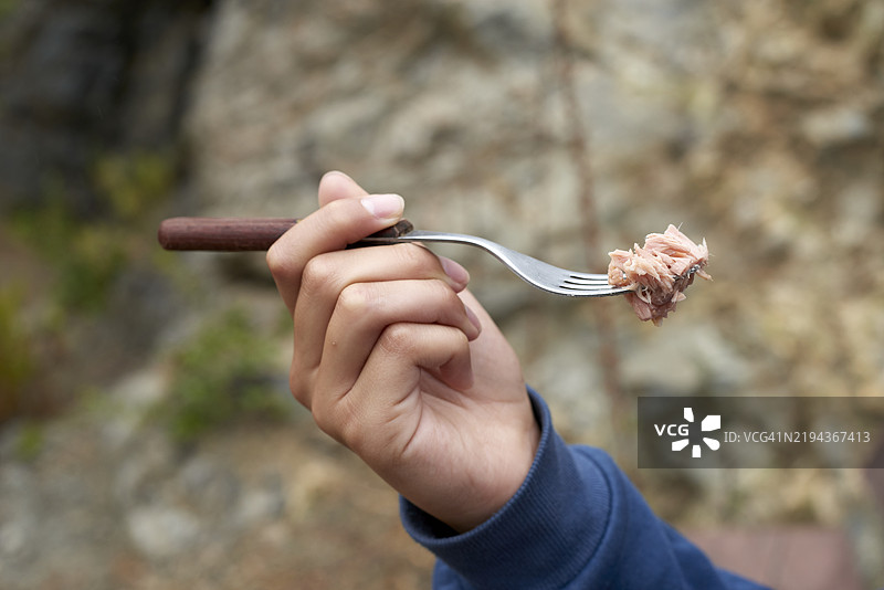 少年在荒野中用叉子吃金枪鱼图片素材