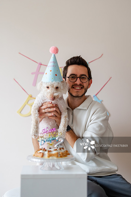 年轻男孩与狗狗一起庆祝生日图片素材