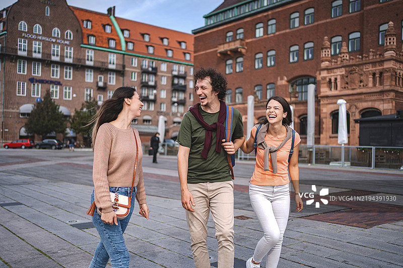 三位年轻人在瑞典马尔默散步时欢笑。图片素材