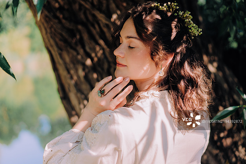 年轻女性在树下阳光与阴影中享受大自然图片素材