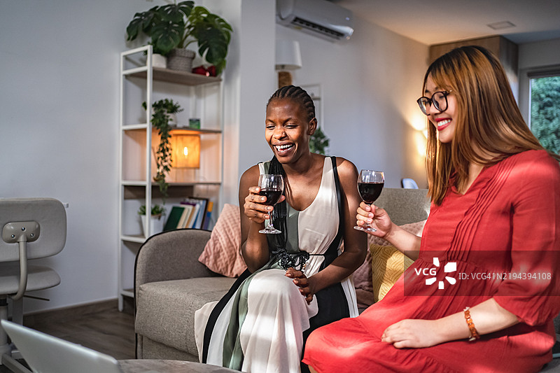 两位年轻女性在家中视频通话并喝酒图片素材