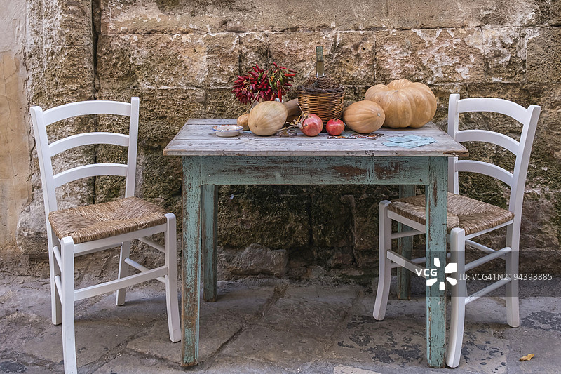 在阿普利亚的加利波利小巷中，装饰有桌子、椅子和秋季蔬菜。图片素材