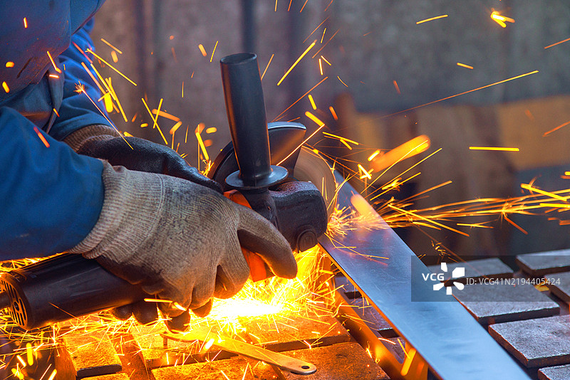 工人在车间使用磨光机塑形金属，火花四溅。图片素材