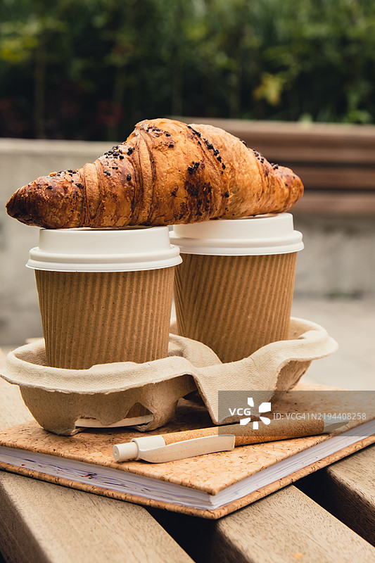 新鲜出炉的巧克力可颂面包放在两个带盖的茶杯上图片素材