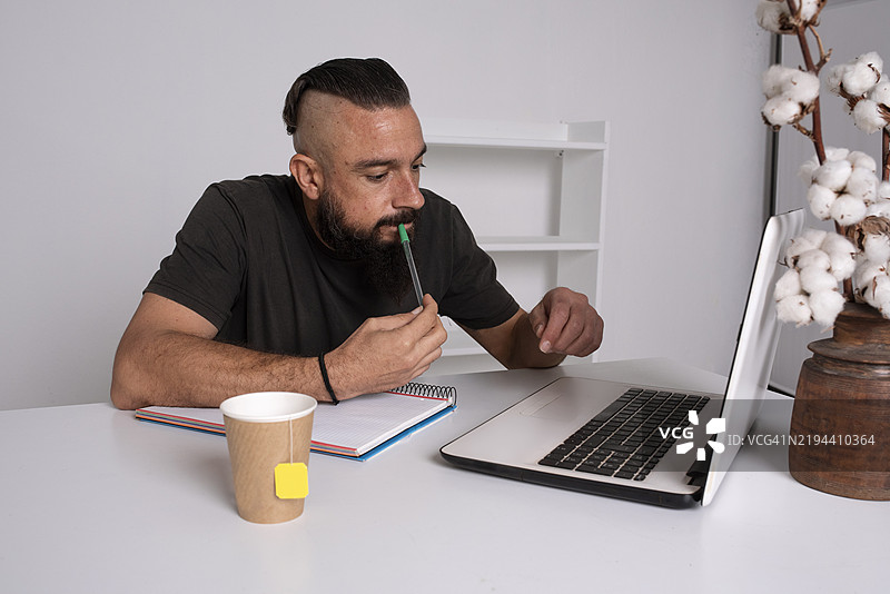 一个男人在用笔记本电脑和笔记本学习的横向视图图片素材