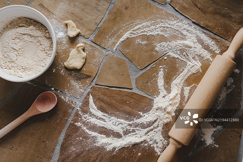 从上方俯视一张石制厨房桌，上面撒满了面粉和一个擀面杖。图片素材